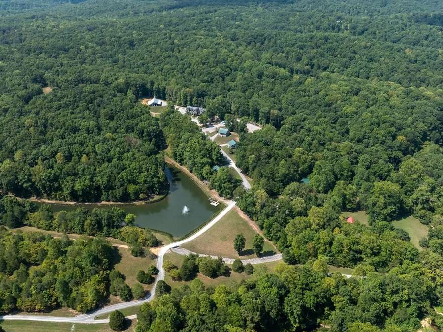 Aerial view of the property: wooded hills, a lake, and gravel roads winding through.